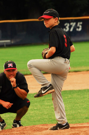 Boy getting reach to pitch on a baseball mound.
