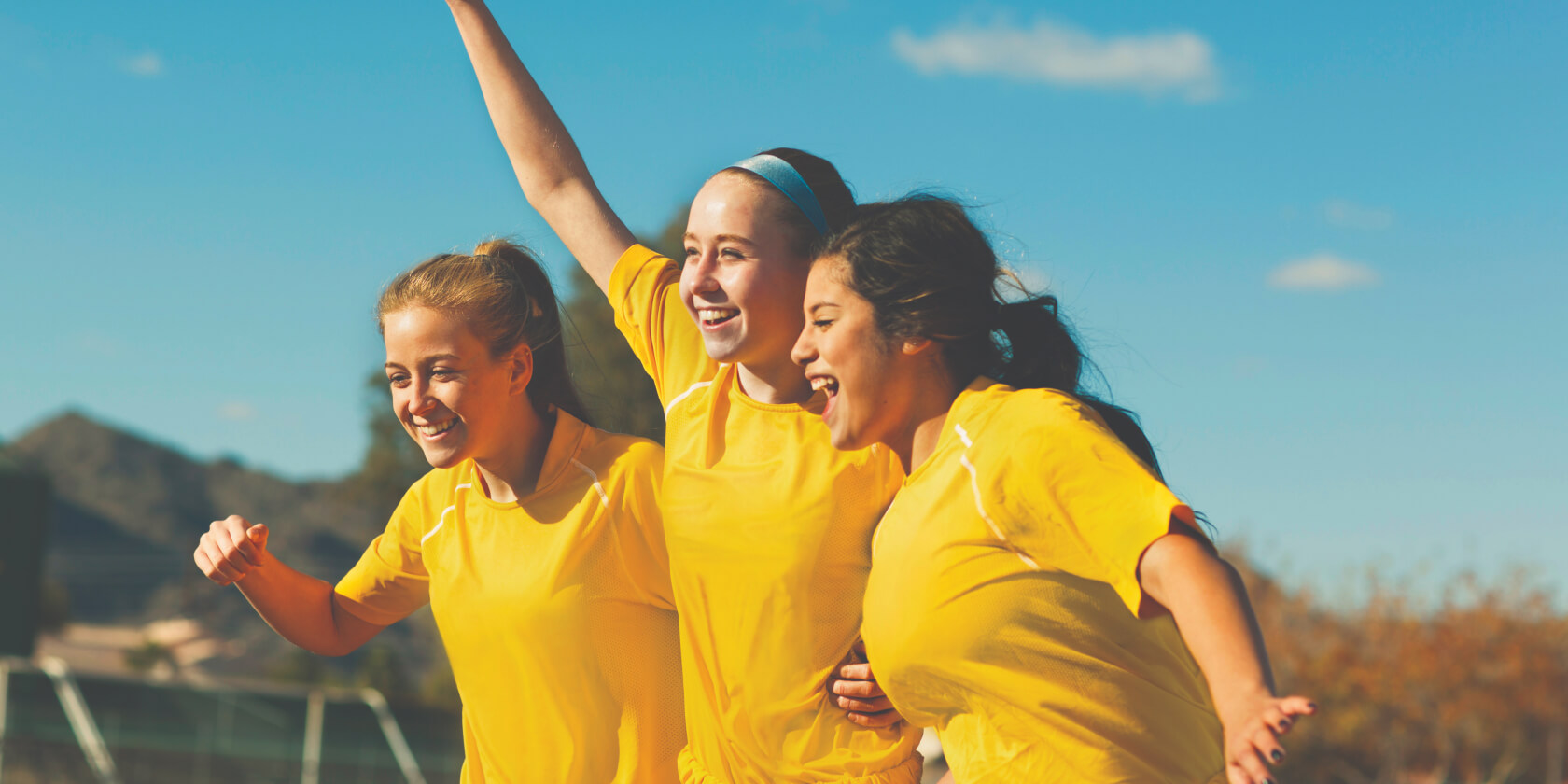 Girls in soccer uniforms smiling together.