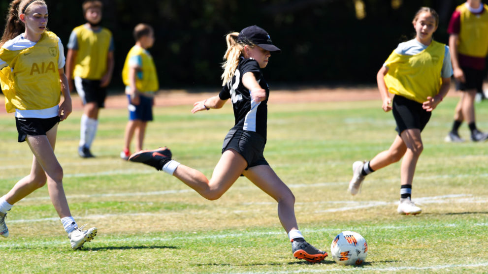 Girl about to kick the soccer ball during a game.