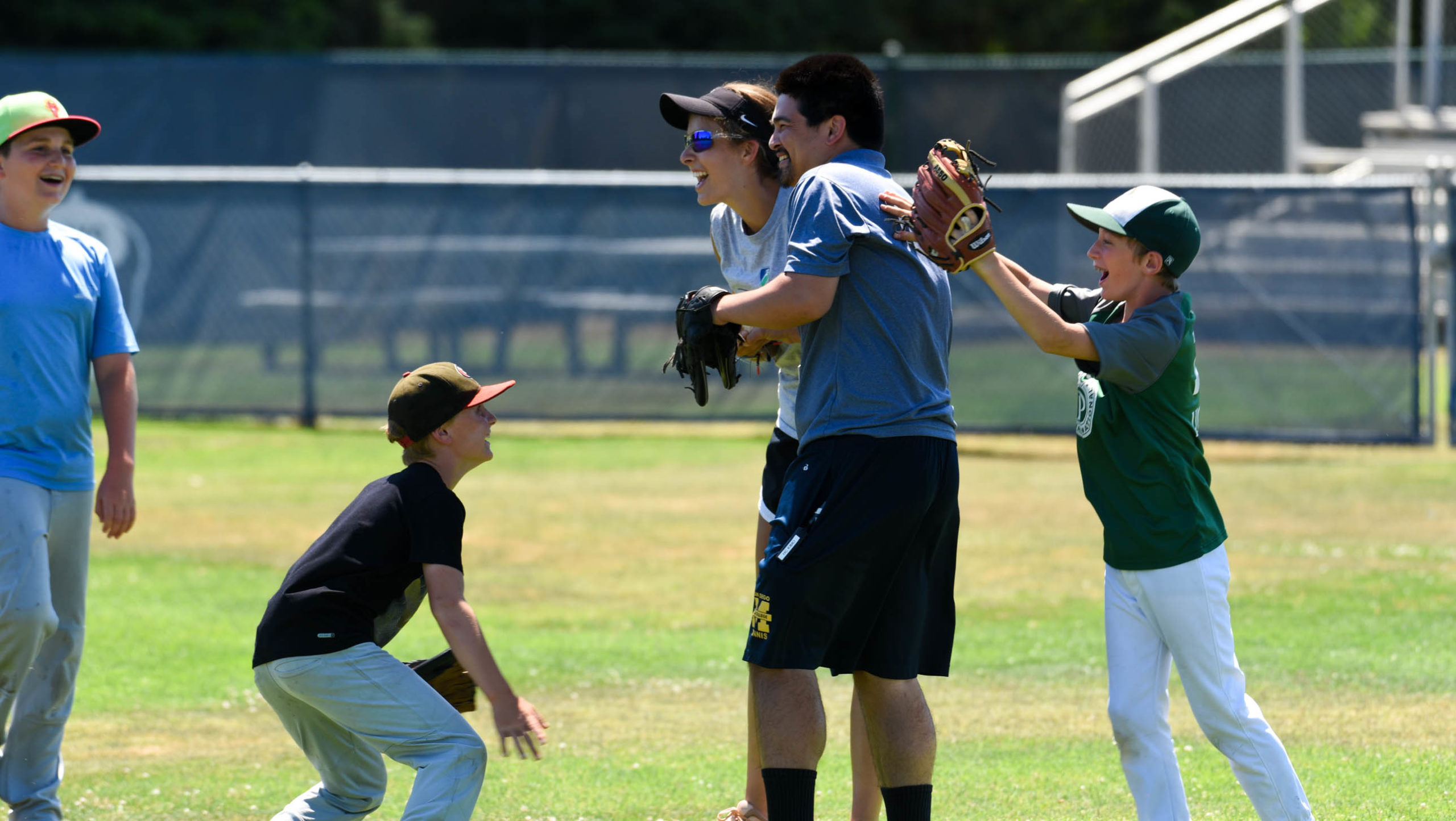 Baseball campers celebrating with staff member on the field.