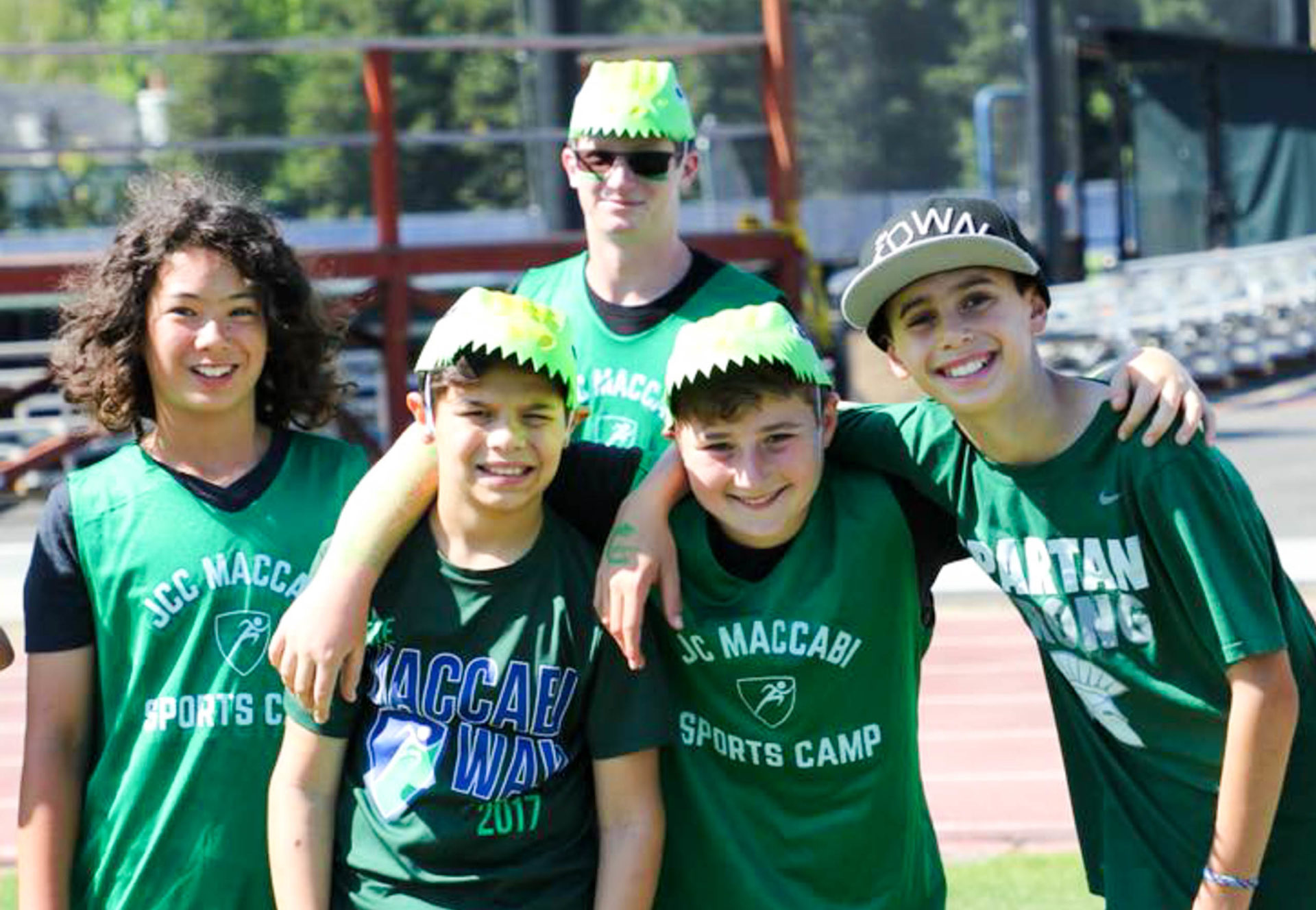A few campers all in green camp shirts taking a photo together with arms around each other.