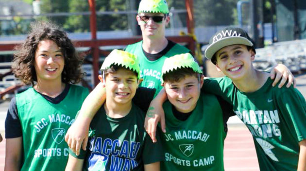 A few campers all in green camp shirts taking a photo together with arms around each other.