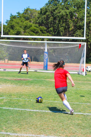 Girl about to kick soccer ball into goal.