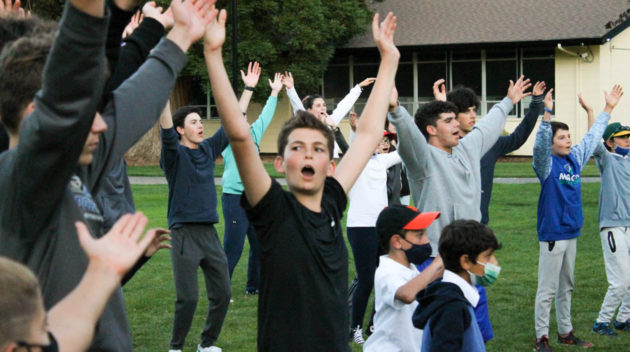 Kids enthusiastically raising their hands at Sabbath.