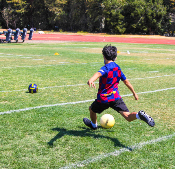 Camper running and getting ready to kick a soccer ball.