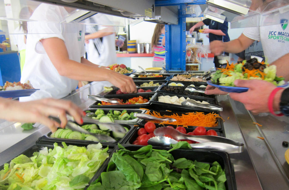 Campers serving themselves salad from the salad bar.