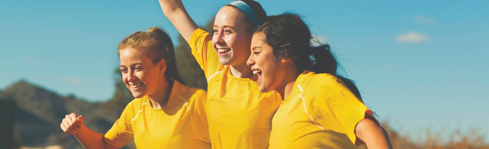 Girls in soccer uniforms smiling together.