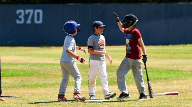 Rookie campers giving high fives on the baseball field.