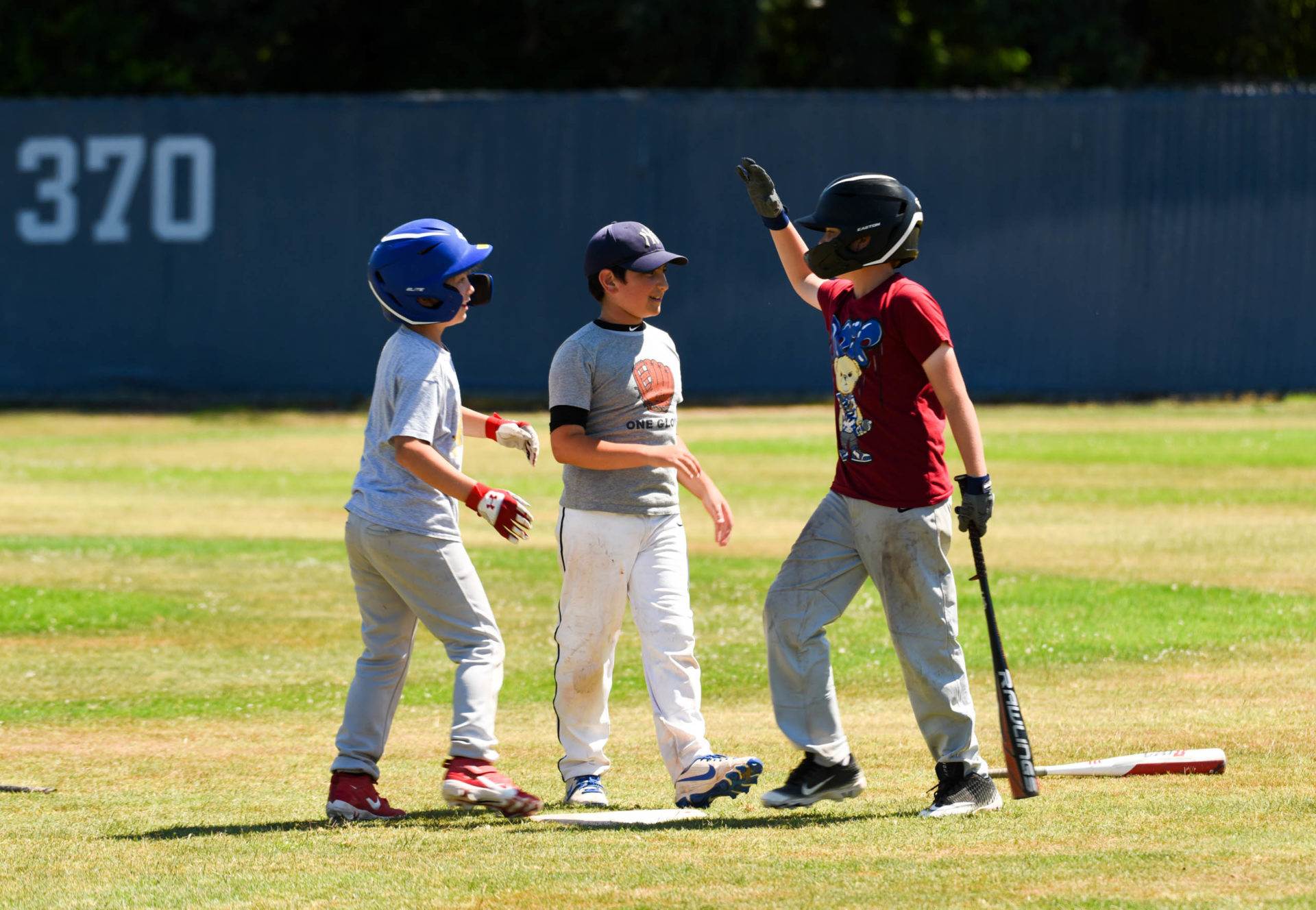 Rookie campers giving high fives on the baseball field.