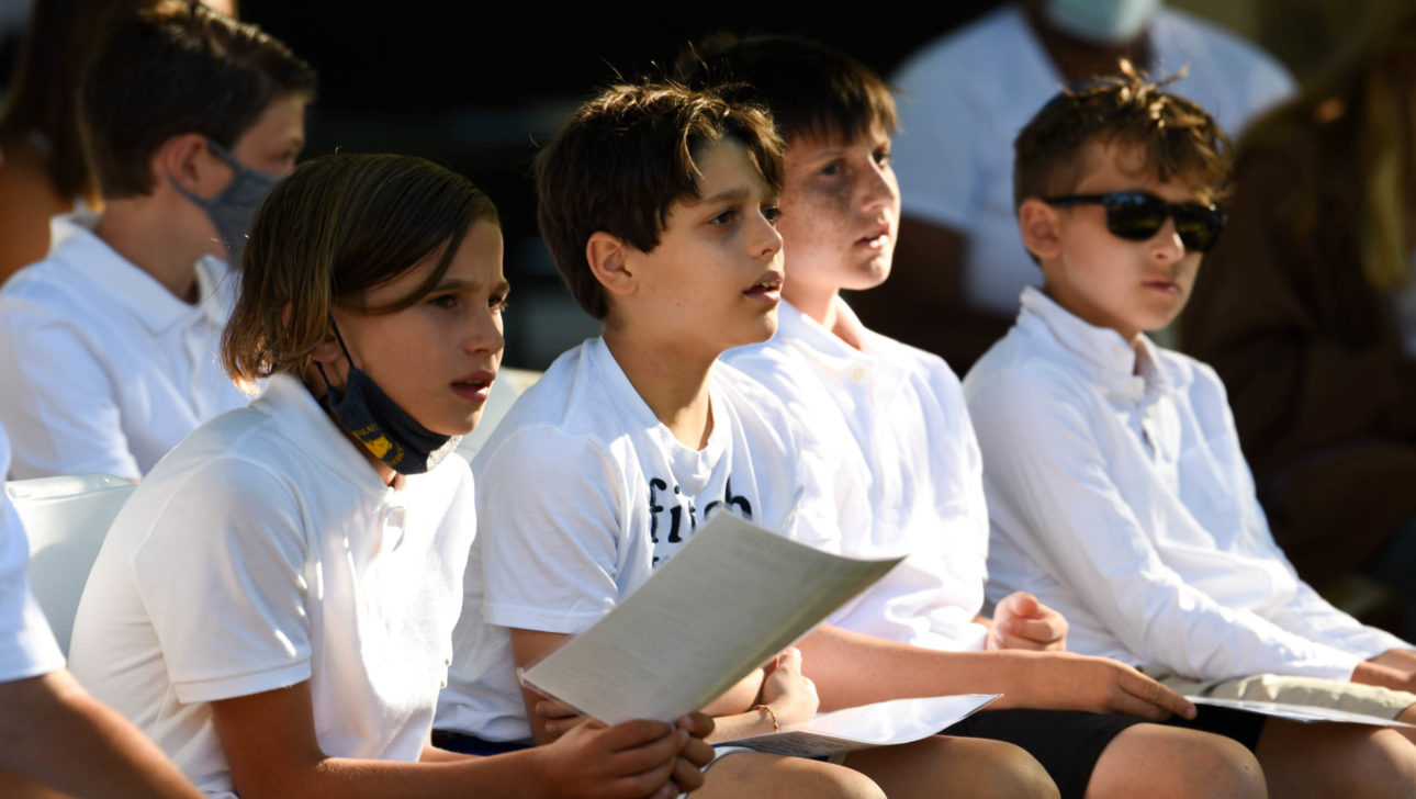 Campers sitting together reading a paper at Shabbat service.
