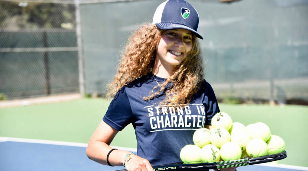 Camper with a stack of tennis balls on her raquet.