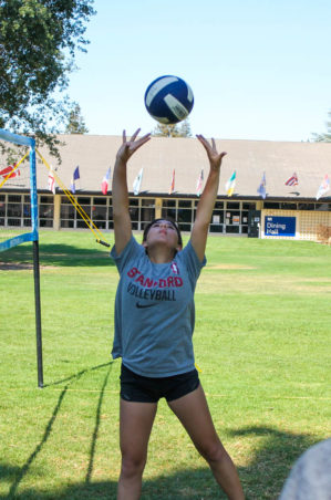 Girl playing volleyball on a grass court.
