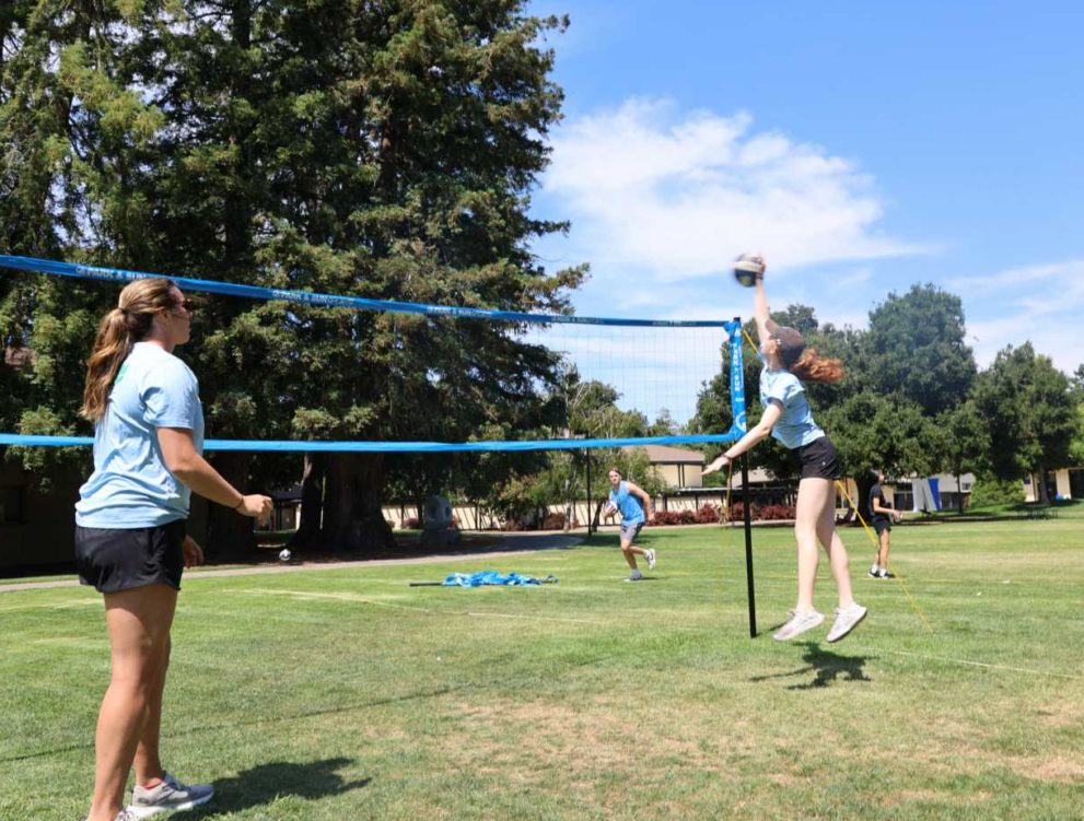 girl spikes ball over net in volleyball